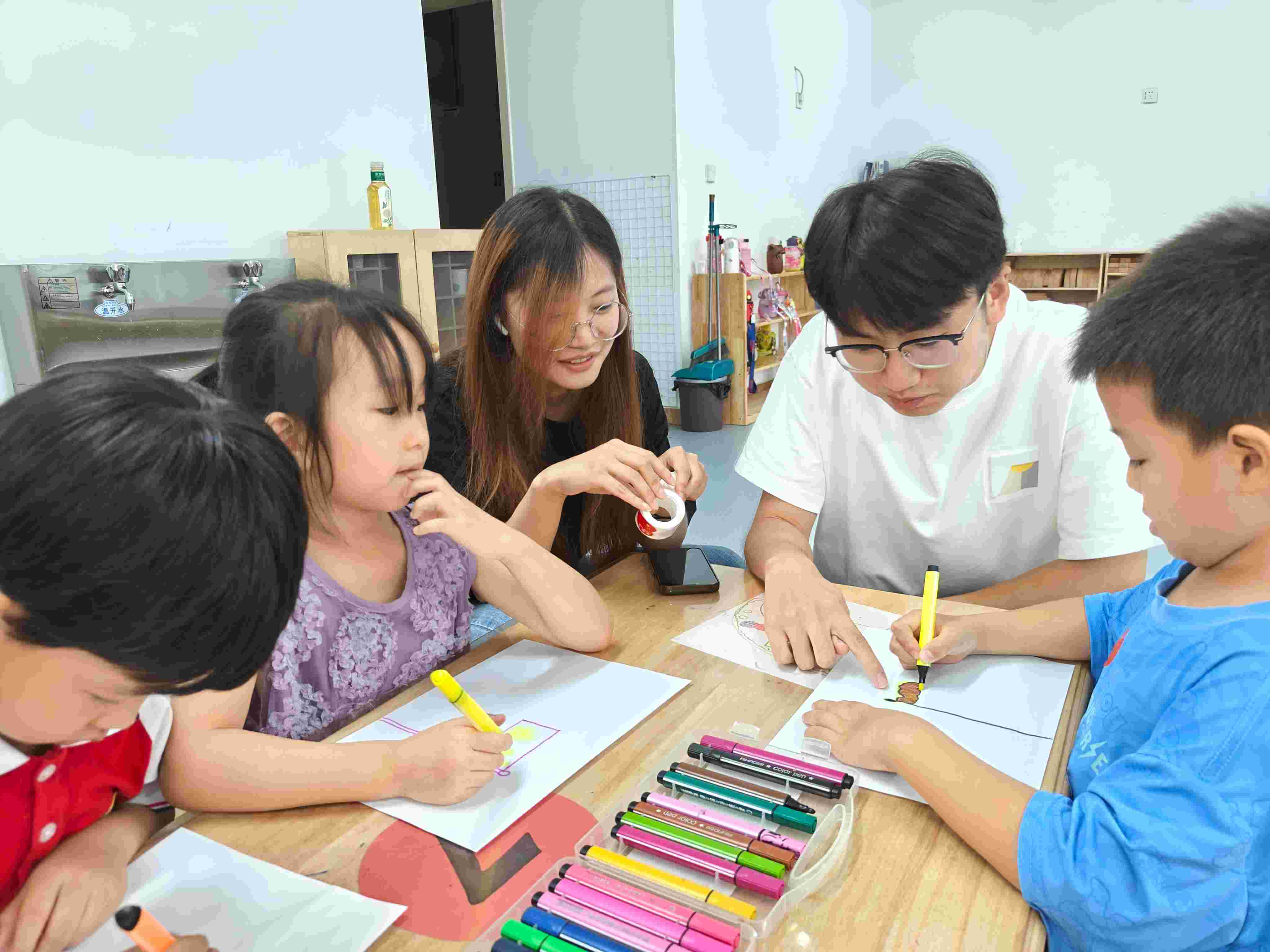 圖為實踐團(tuán)成員宋立豪、譚依然在協(xié)助小朋友們完成畫作